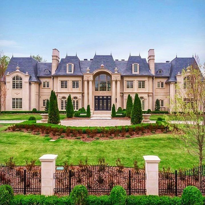 a large house with lots of windows and bushes in front of the entrance to it