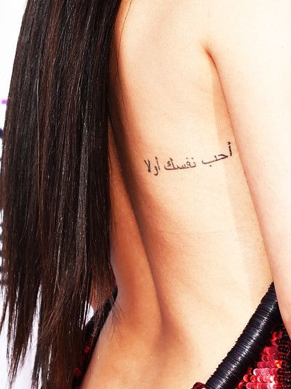 the back of a woman's body with arabic writing on her left shoulder and right arm