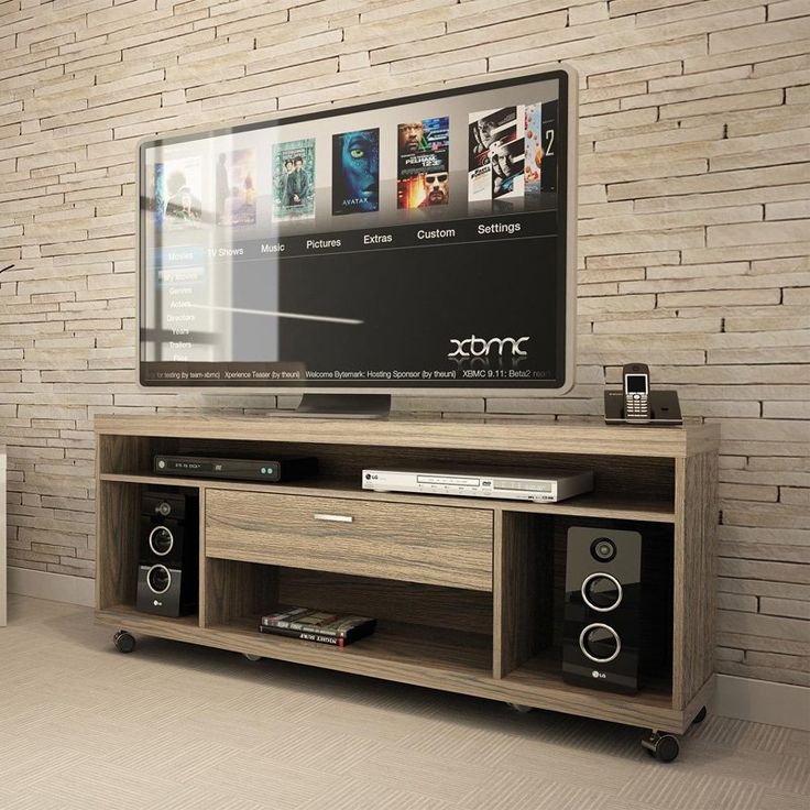 an entertainment center with two speakers and a large television on top of it in front of a brick wall