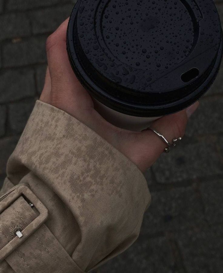 a person holding a black coffee cup in their hand