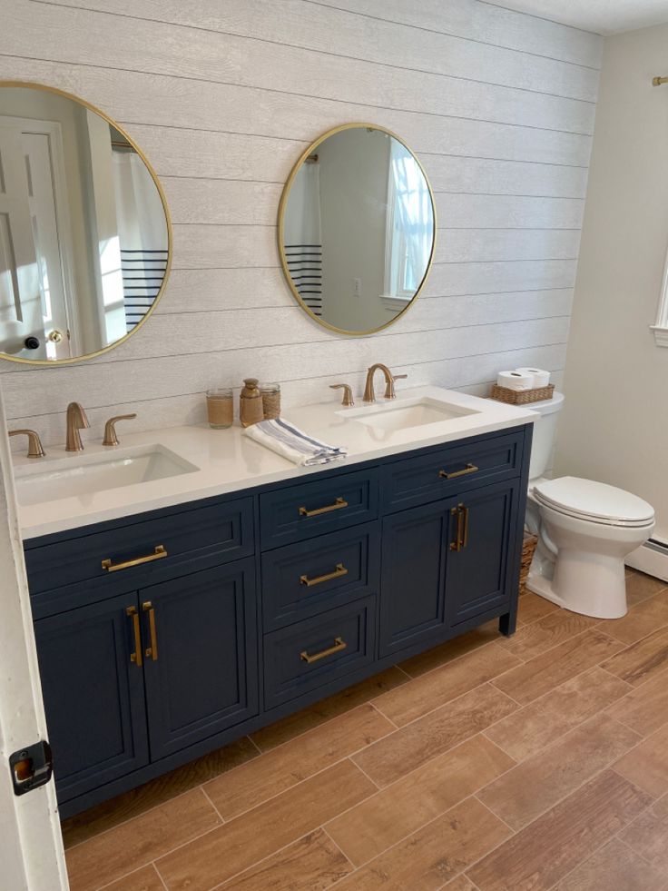 a bathroom with two sinks, mirrors and a toilet in the middle of the room