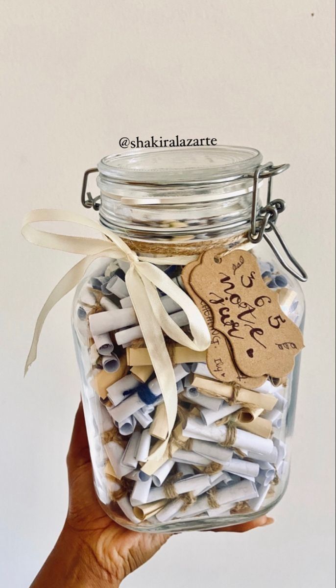 a hand holding a jar filled with lots of clothes pins and paper clippings