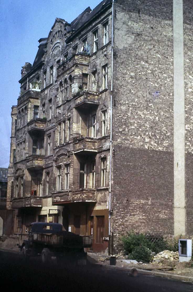 an old building with many windows and balconies next to a truck on the street