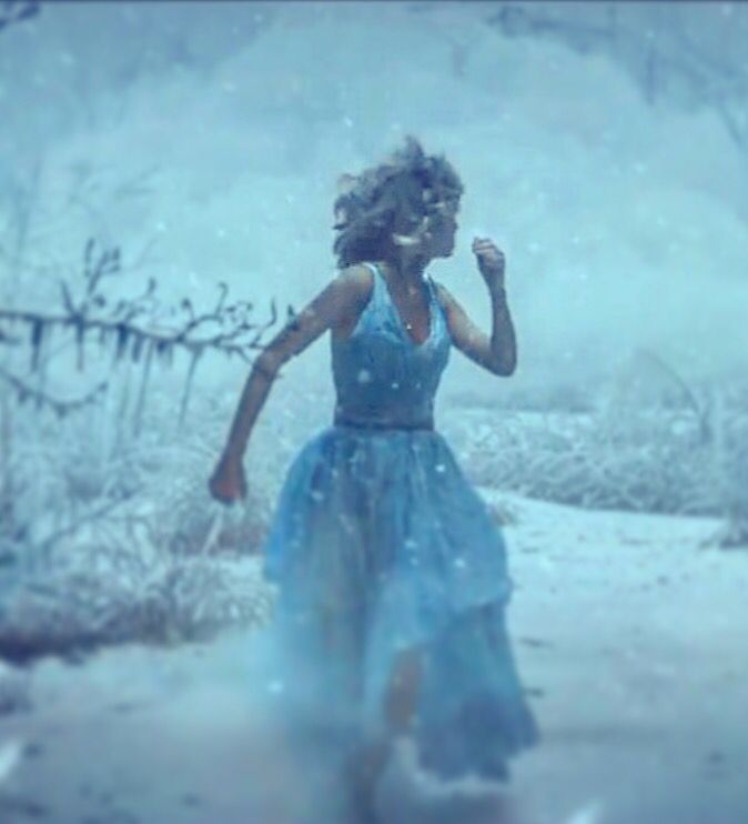 a woman in a blue dress walking through the snow