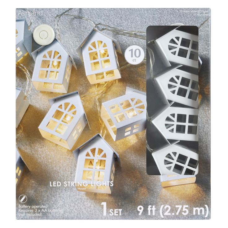 some white and gold paper houses are on the ground with string lights attached to them