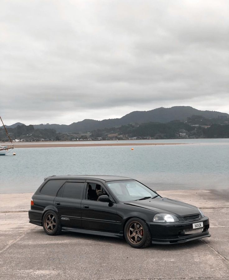 a small black car parked in front of a body of water