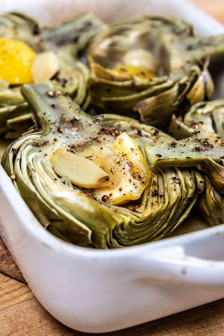 artichokes in a white dish with an egg on top and seasoning