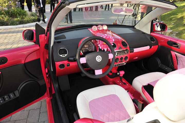 the interior of a pink and white car with flowers on it's dash board