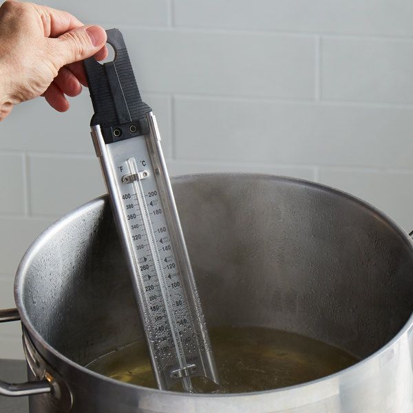 a person holding a thermometer over a pot