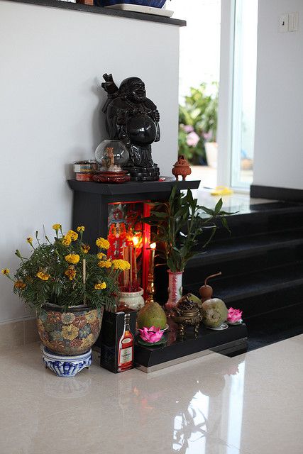 there are many flowers and candles on the shelf next to the stairs that lead up to the second floor