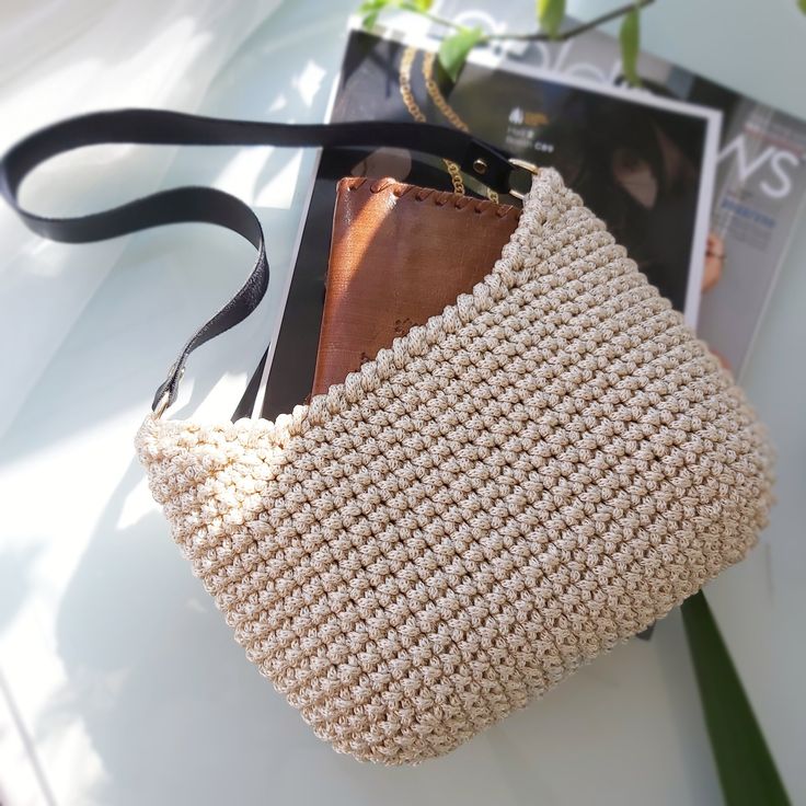 a white purse sitting on top of a table next to a plant and magazine holder