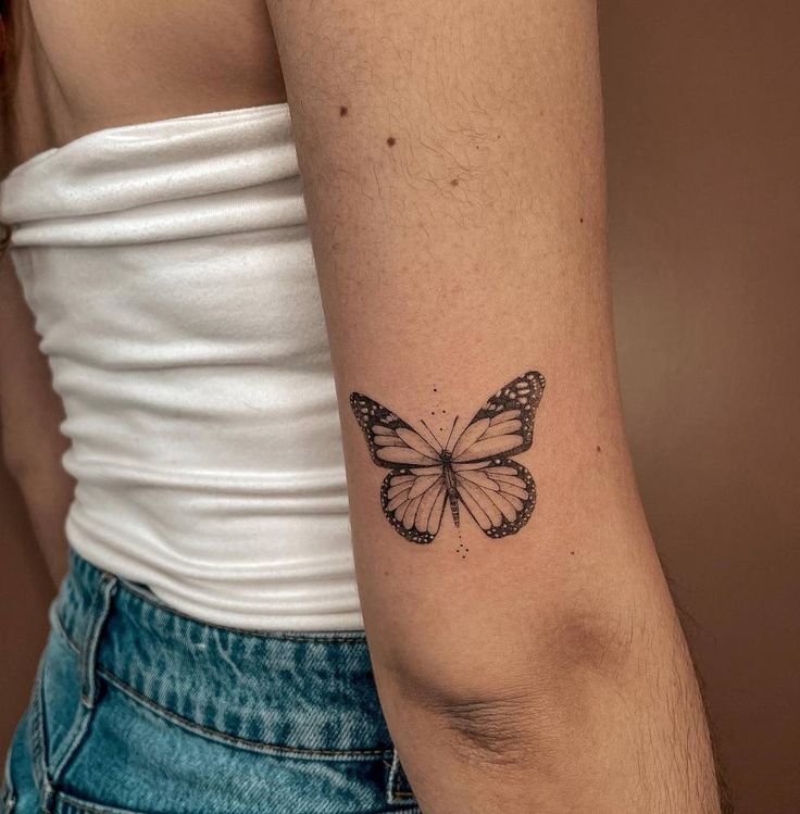 a woman's arm with a small butterfly tattoo on the back of her left arm