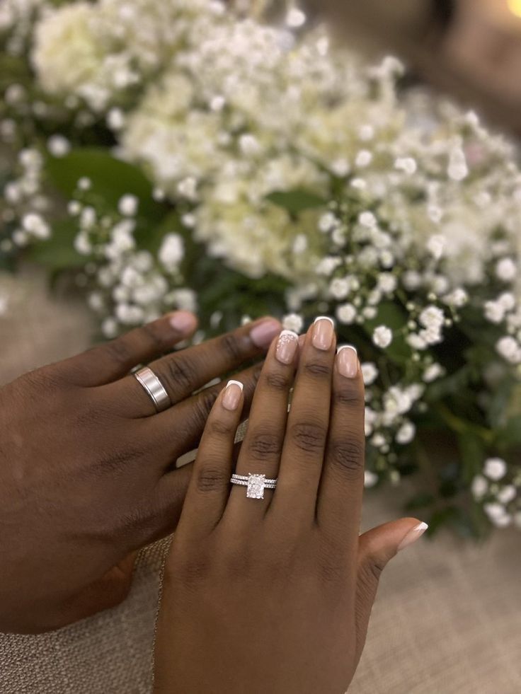 two people holding each other's hands with flowers in the background