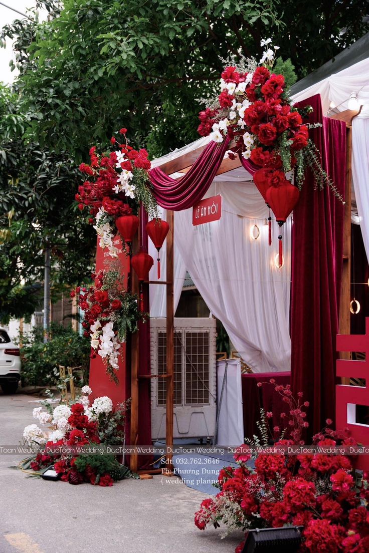 a red and white wedding arch decorated with flowers