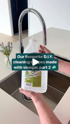 a person holding a bottle of cleaner in front of a sink