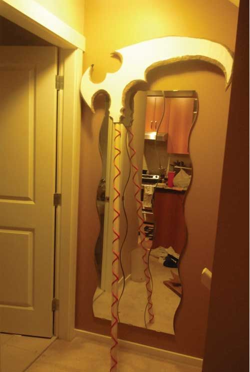 a mirror that is in the middle of a room with a light on and red streamers hanging from it