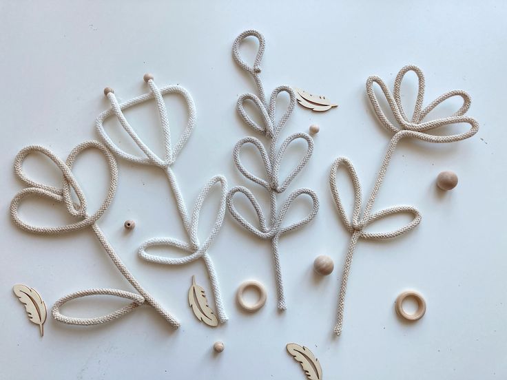 some white string and beads are laying on a table with two flowers in the middle