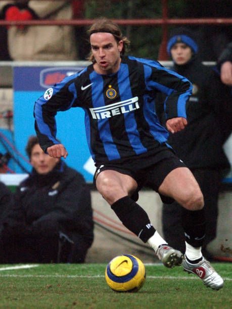 a man kicking a soccer ball on top of a field