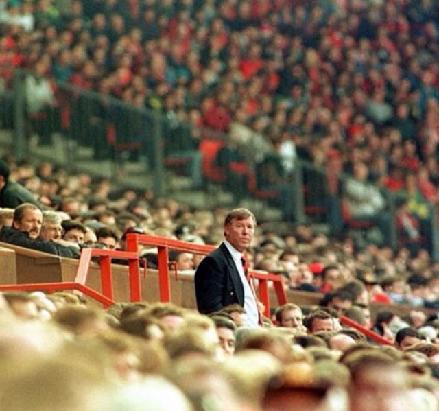 a man standing in front of a crowd of people at a sporting event with red railings