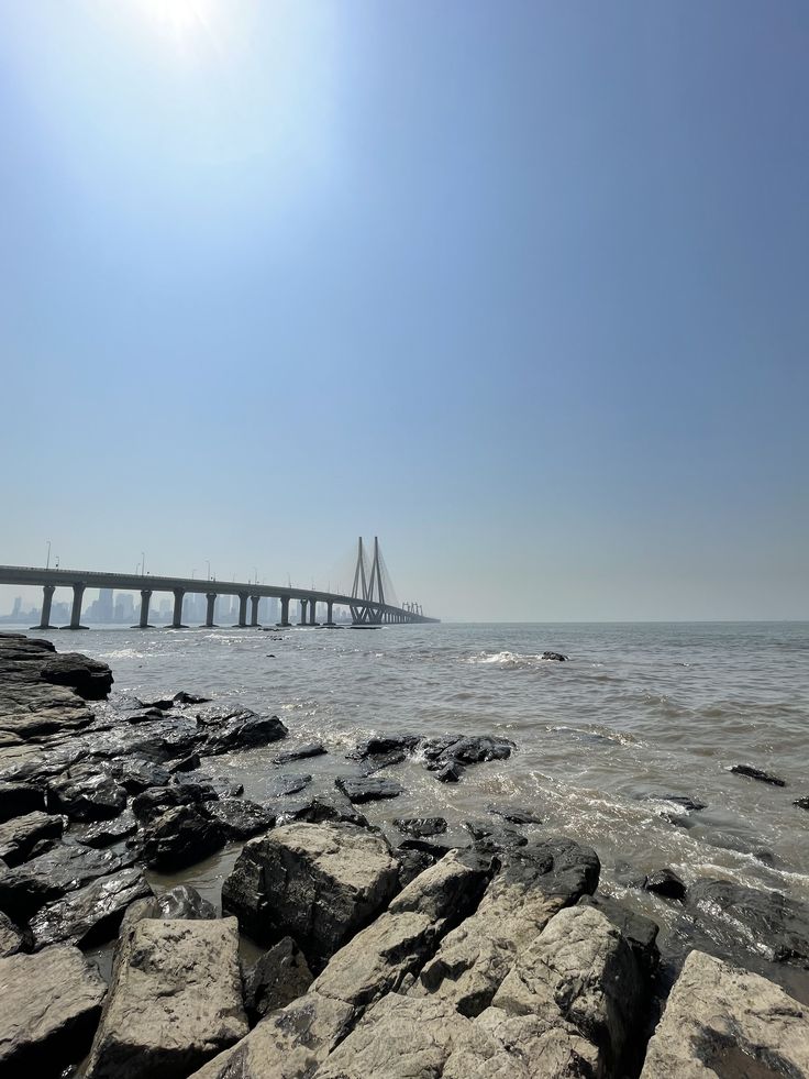 there is a bridge that goes over the water and rocks in front of it,