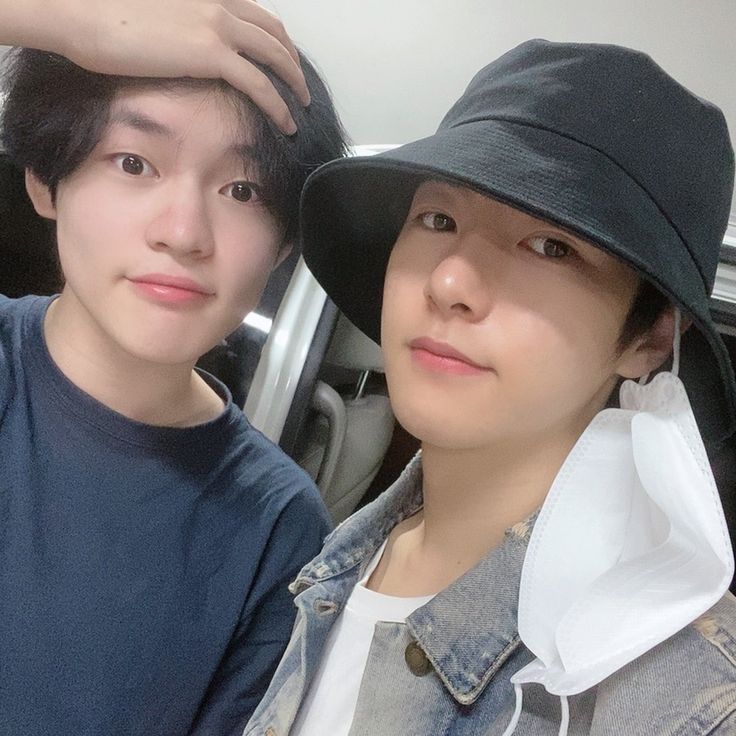 two young men wearing hats are posing for a photo in front of a car door