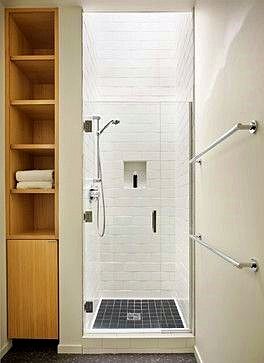 a walk in shower sitting next to a wooden shelf