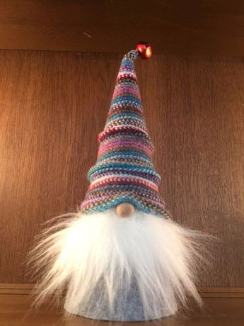 a knitted gnome's hat with white feathers and red nose on a shelf