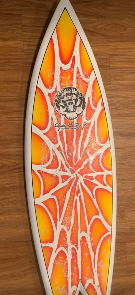 an orange and white surfboard sitting on top of a wooden floor