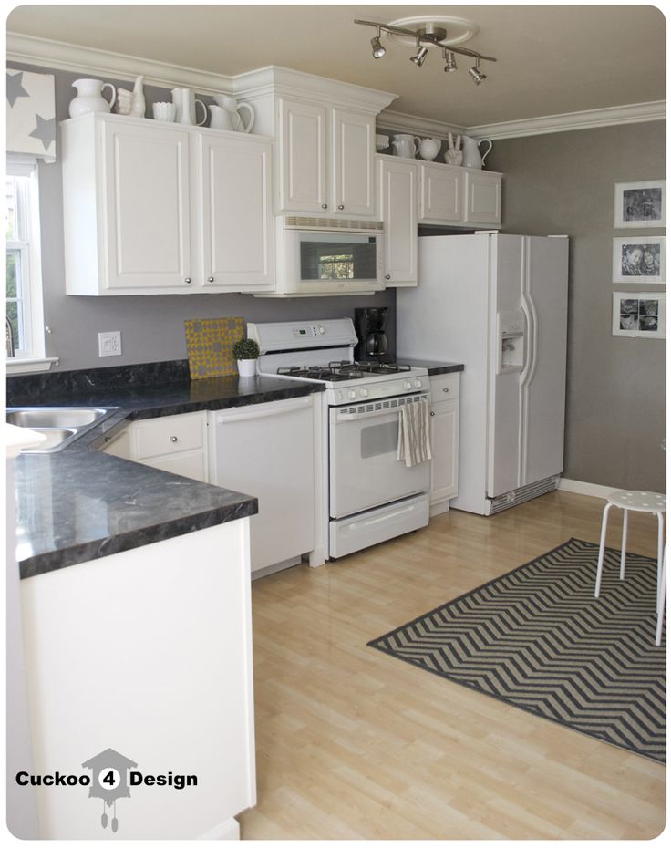 a kitchen with white cabinets and black counter tops is pictured in this image, there is a rug on the floor next to the stove