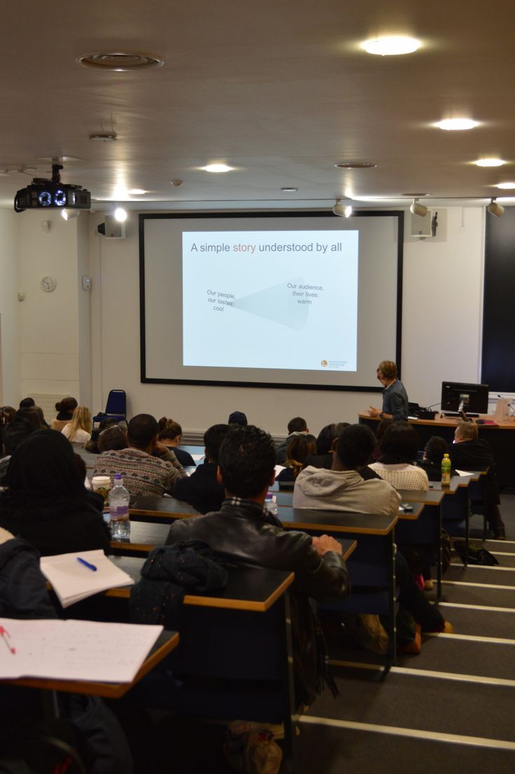 people sitting at desks in front of a projector screen with a presentation on it