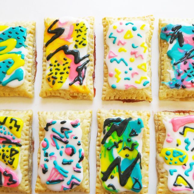 six square decorated cookies sitting on top of each other with icing and sprinkles