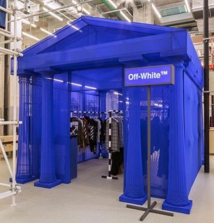 the inside of a clothing store that is blue and has clothes on display in it