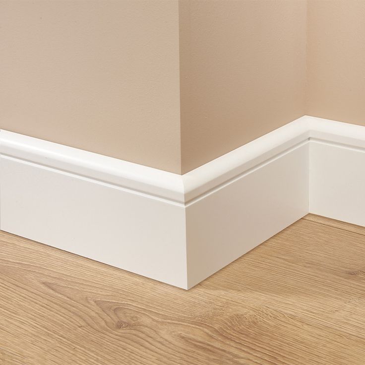 the corner of a room with wood flooring and white mold moulder trim