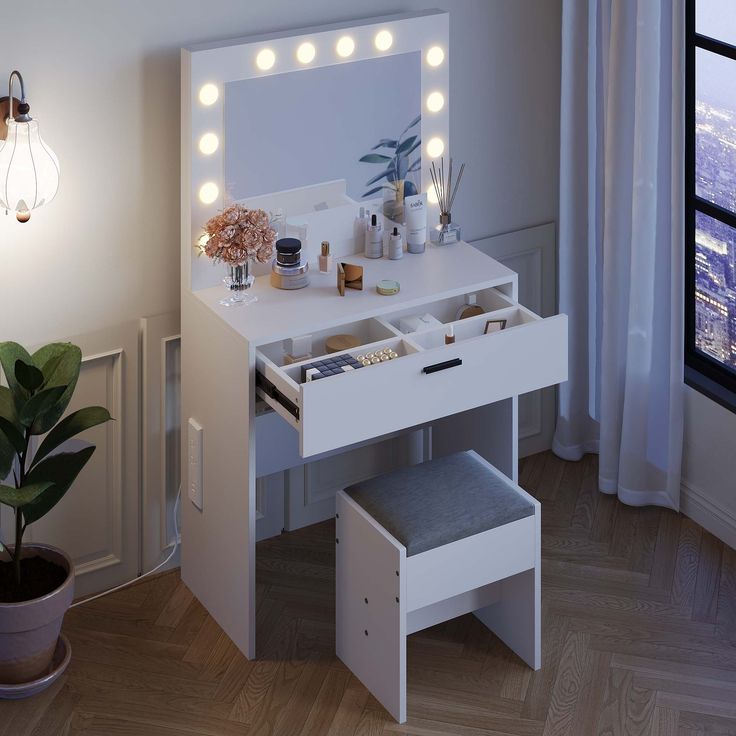 a white vanity with lights on it next to a potted plant