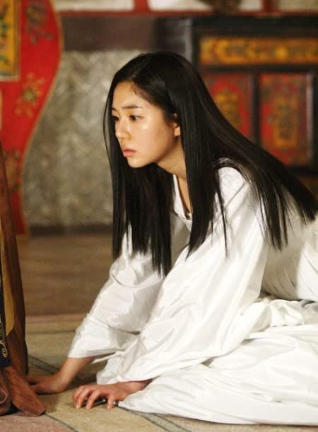 a young woman sitting on the floor next to a wooden chair