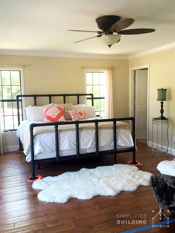 a bed room with a neatly made bed and a ceiling fan in the middle of it