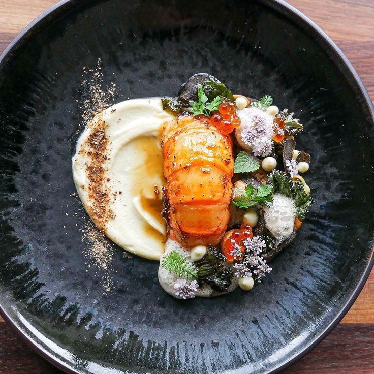 a black plate topped with food on top of a wooden table