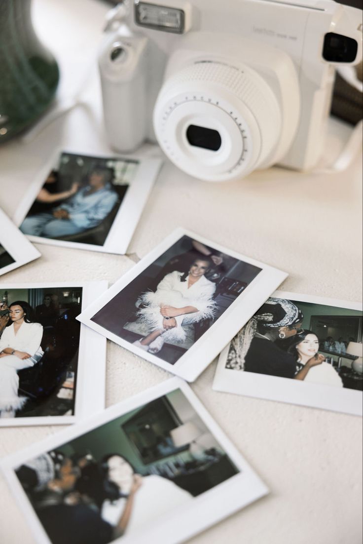 many polaroid photos are laying on the table next to a camera