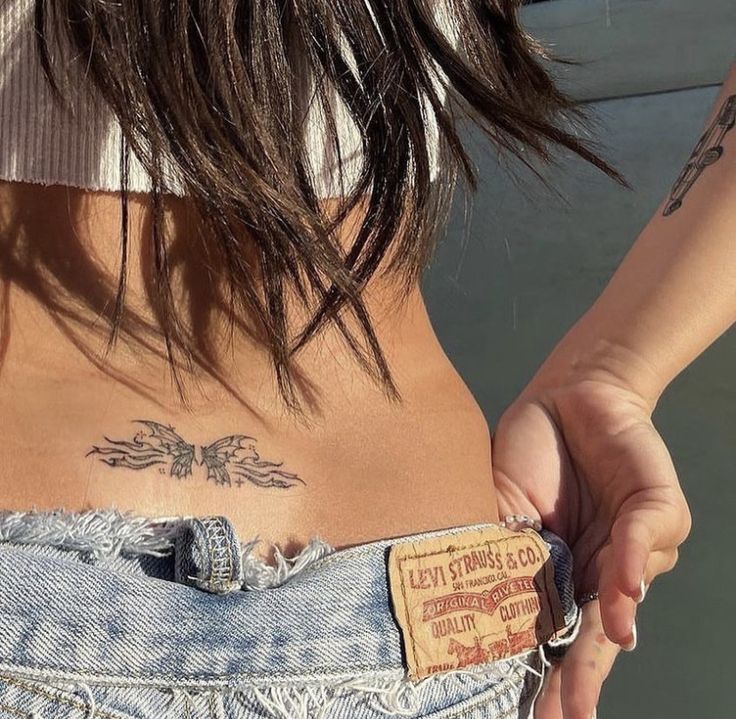 the back of a woman's stomach with tattoos on her left side and chest