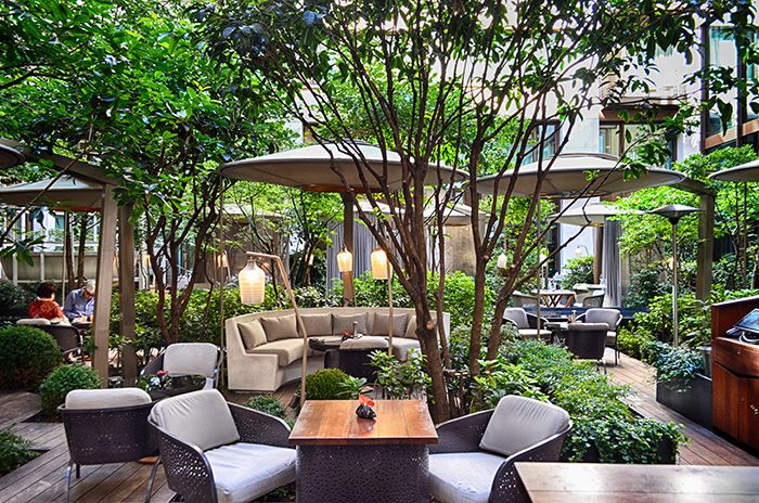 an outdoor seating area with tables, chairs and umbrellas in the middle of it