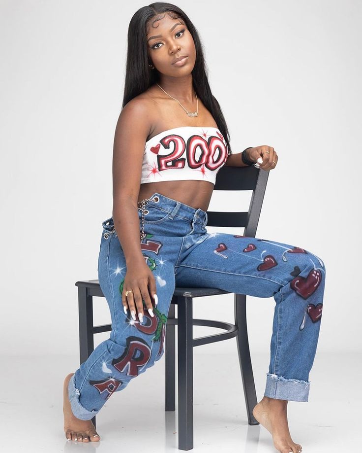 a woman sitting on top of a chair with her legs crossed and wearing ripped jeans