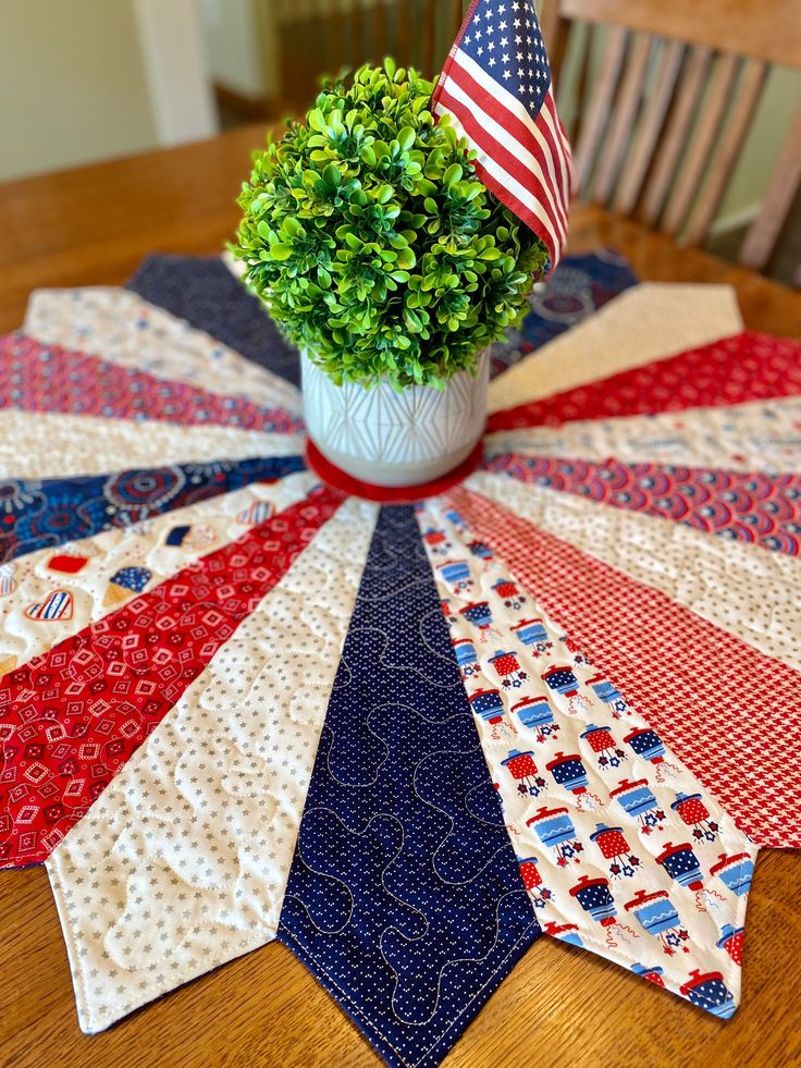 a potted plant sitting on top of a wooden table next to an american flag quilt