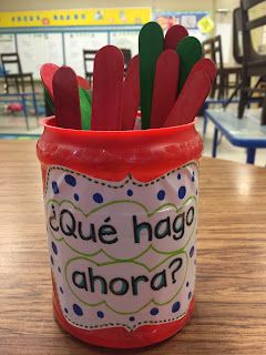 a jar filled with red toothpicks sitting on top of a wooden table in a classroom