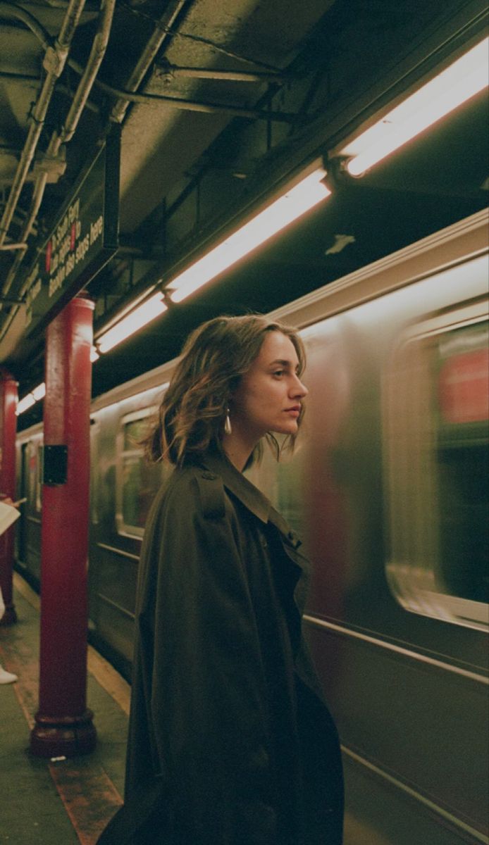 a woman is waiting for the subway to stop