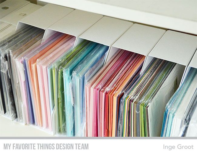 many different colored papers are stacked up on a shelf