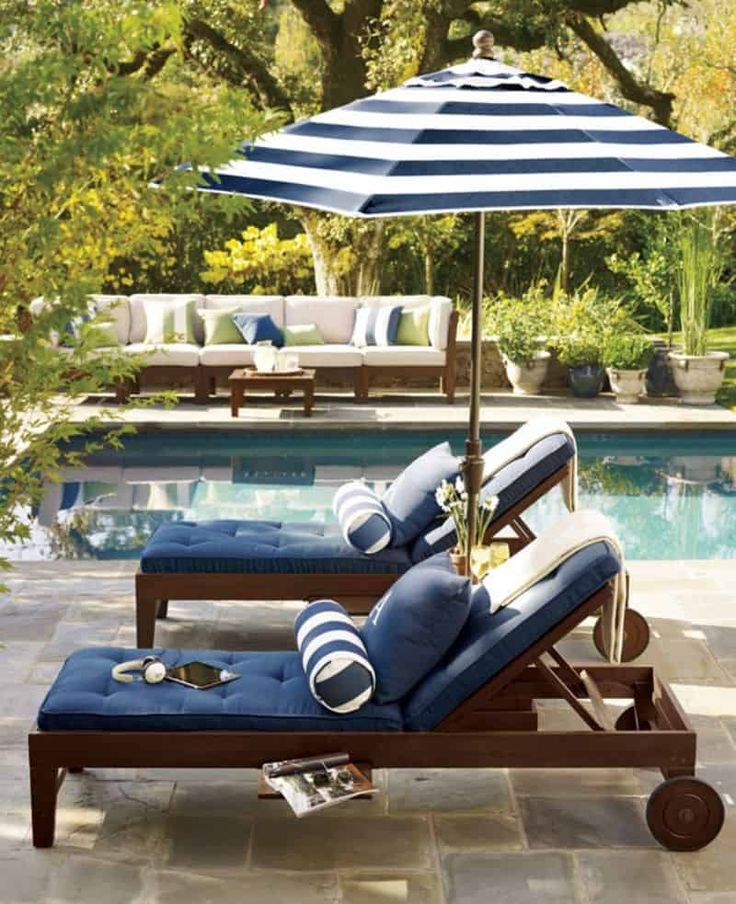 an umbrella and lounge chair next to a pool