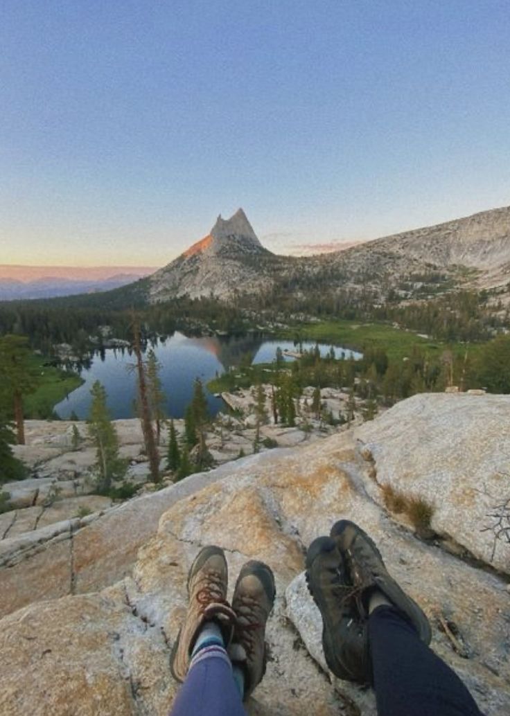 a person sitting on top of a rock next to a lake