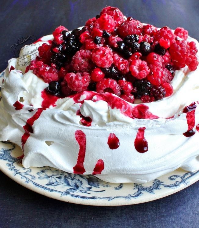 a cake with berries and whipped cream on it sitting on a blue tablecloth covered plate