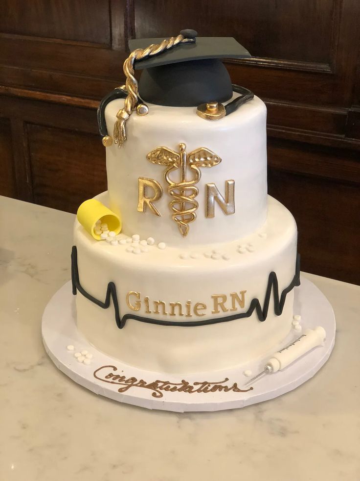 a graduation cake with a stethoscope and mortare on top, sitting on a table