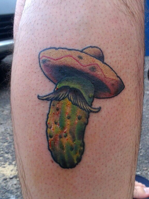 a tattoo on the leg of a man with a hat and cactus in his hand